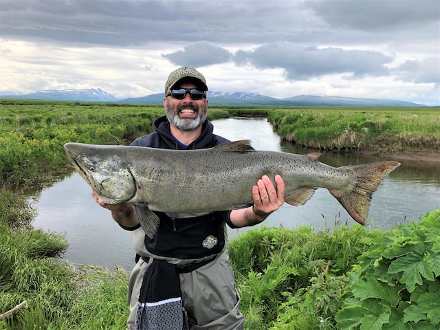 Man smiling and holding a massive king salmon