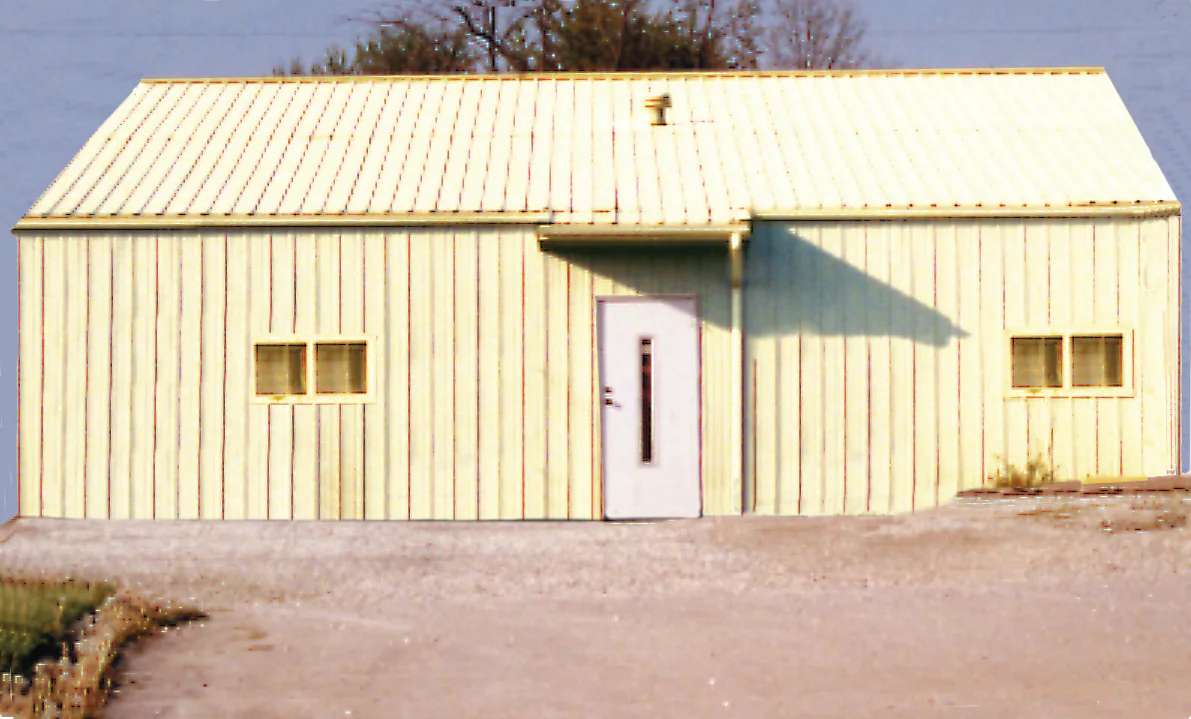 An old, yellow, tin building with a white door. This was the original Midway building